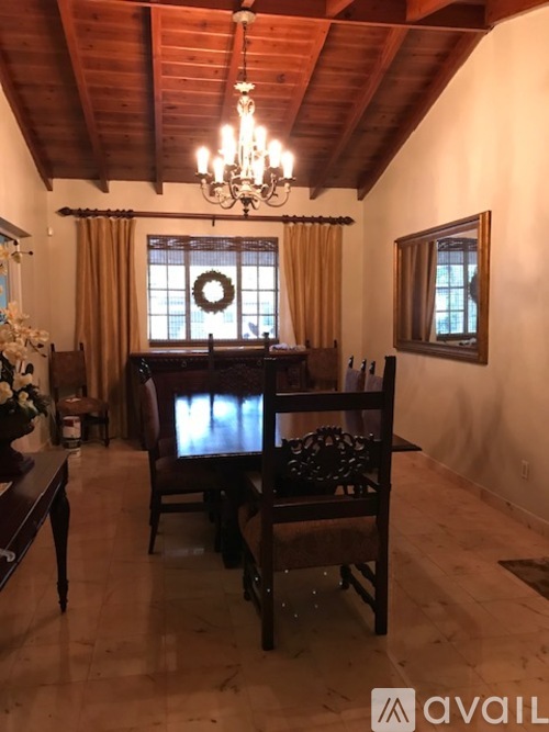 A chandelier hangs from the ceiling in a room with wooden floors and furniture.