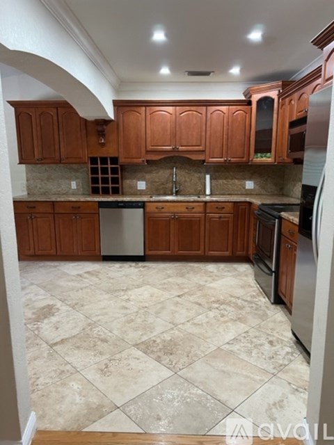 A kitchen with wooden cabinets and a tiled floor.
