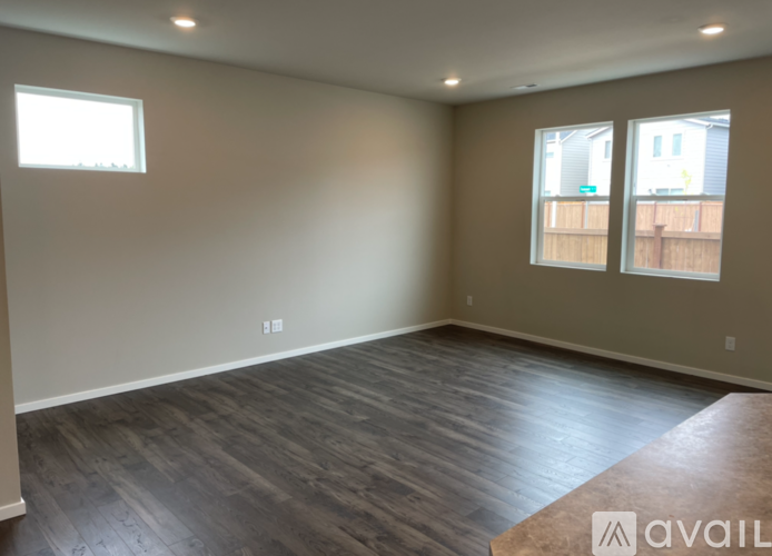 A room with wooden flooring and two windows.