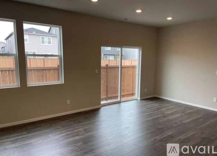 A room with wooden floors and a sliding glass door leading to a backyard.