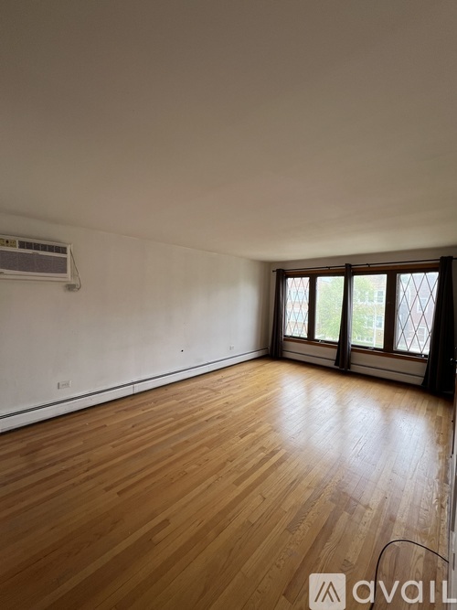 A room with wooden flooring and a window with a view of trees.