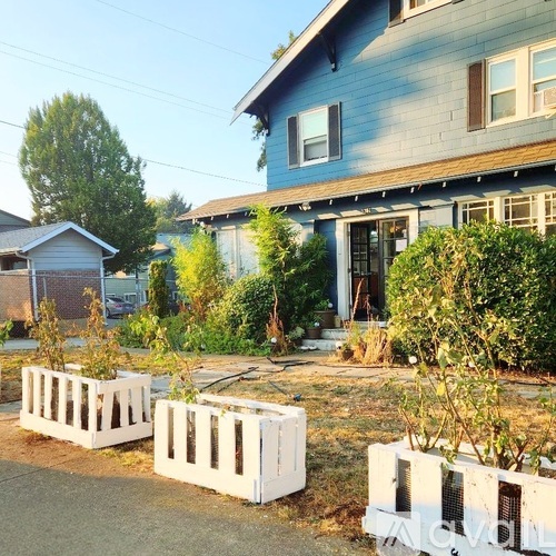A blue house with white fence and bushes in front.
