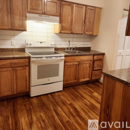 A kitchen with wooden cabinets and a white stove top oven.