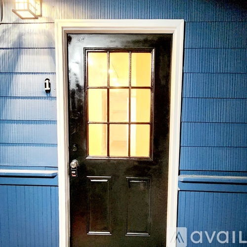 A black door with a glass panel is set in a blue wall.