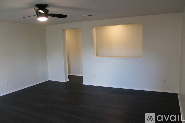 A room with a ceiling fan and two windows.