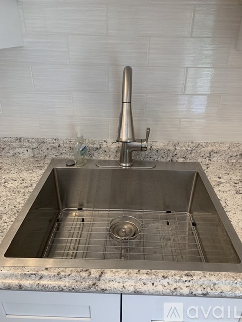 A kitchen sink with a faucet and a drain grid.