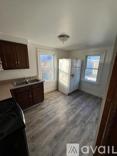 A kitchen with a black dishwasher and wooden cabinets.