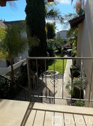 A balcony with a metal railing and a tree in the background.