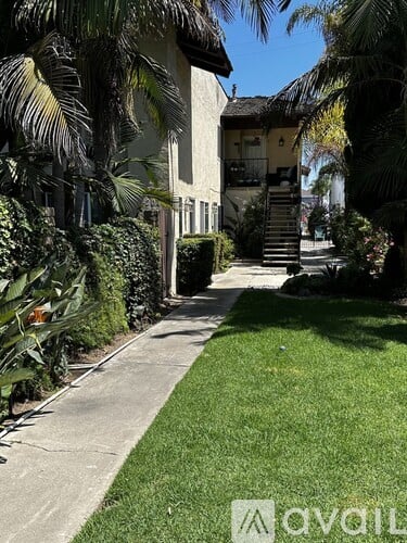 A house with a green lawn and a concrete pathway leading to the front door.
