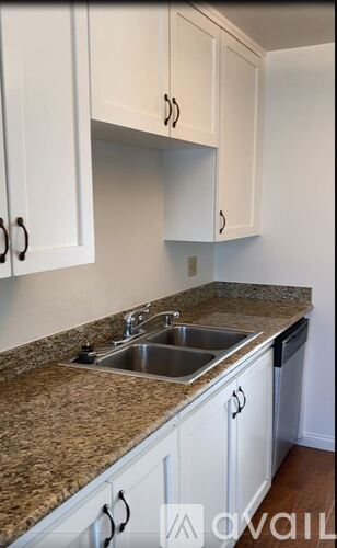 A kitchen with white cabinets and granite countertops.