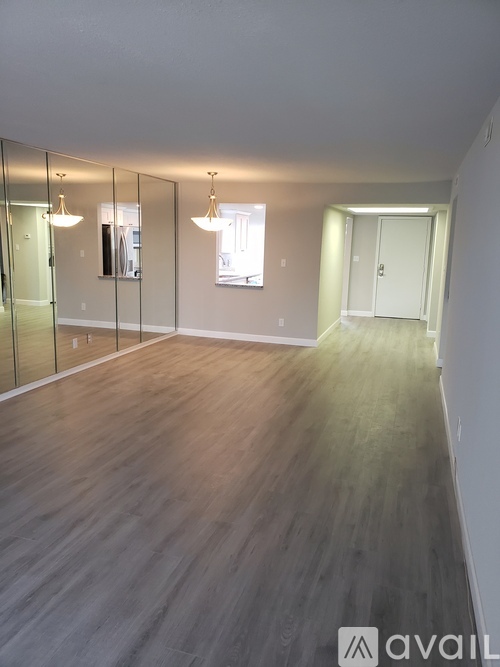 A spacious room with wooden flooring and a large mirror on the wall.