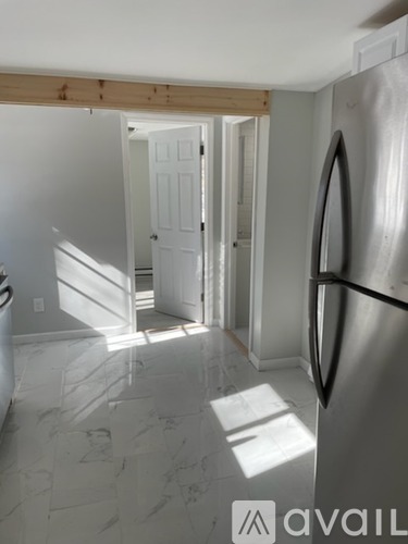 A kitchen with a refrigerator and a doorway leading to another room.