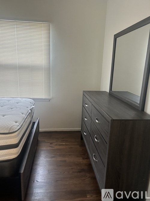 A bedroom with a bed, dresser, and mirror.