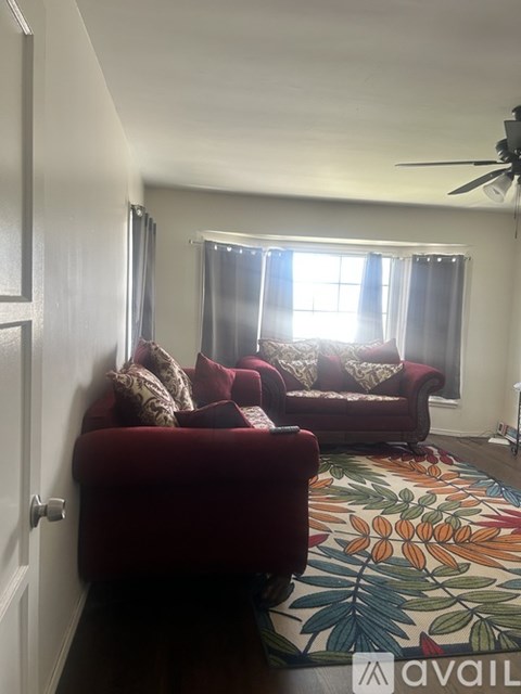 A living room with a red couch and a colorful rug.