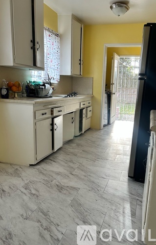 A kitchen with white cabinets and a black fridge.