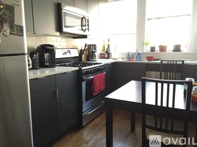 A kitchen with a black stove top oven and a black table with two chairs.