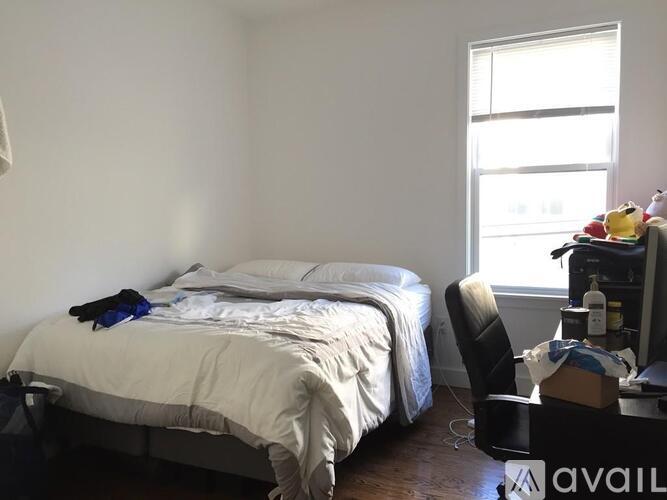 A bedroom with a bed, chair, and window.