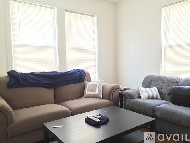 A living room with a brown couch, a grey couch, and a black coffee table.