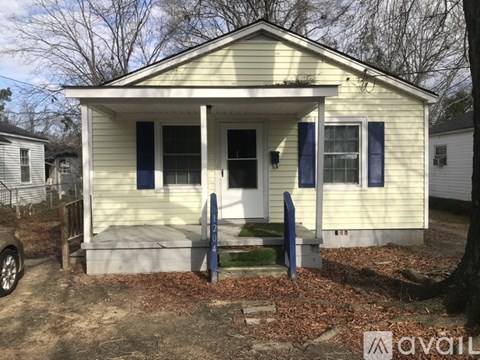 A small house with a porch and a car parked in front.