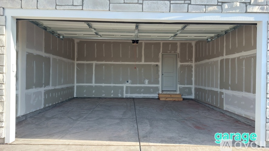 A garage with a white door and walls covered in drywall.
