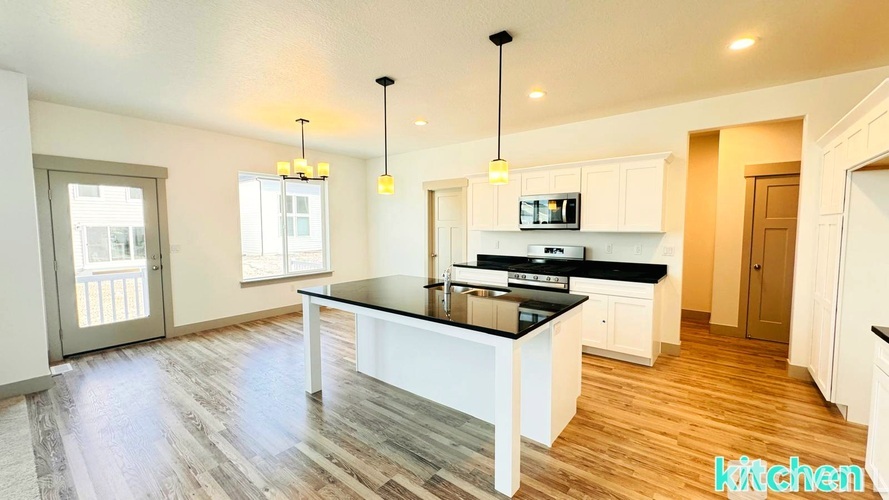A modern kitchen with a large island and pendant lights.