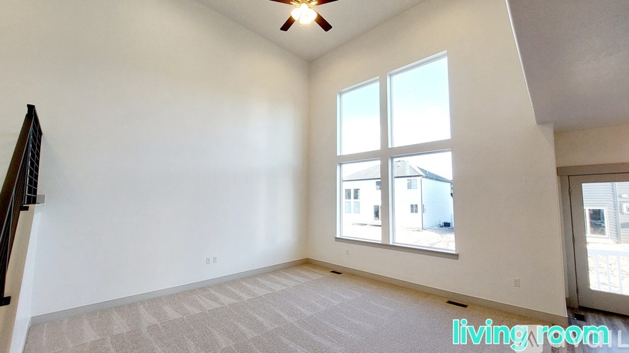 A living room with a carpet floor and a ceiling fan.