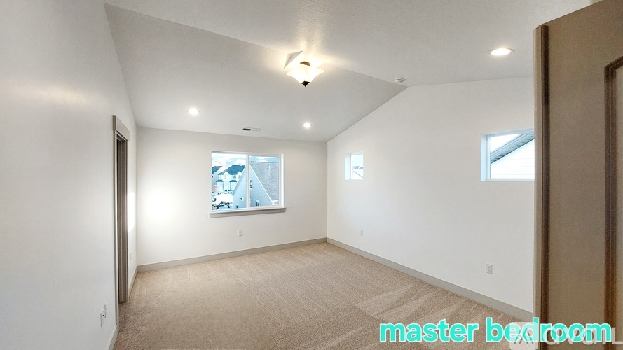 A spacious bedroom with a window and a carpeted floor.