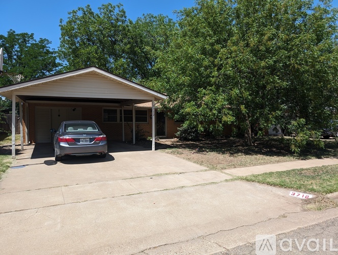 A car is parked in a garage with trees in the background.