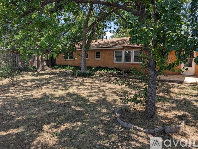 A tree in a yard with a house in the background.