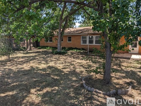 A tree in a yard with a house in the background.