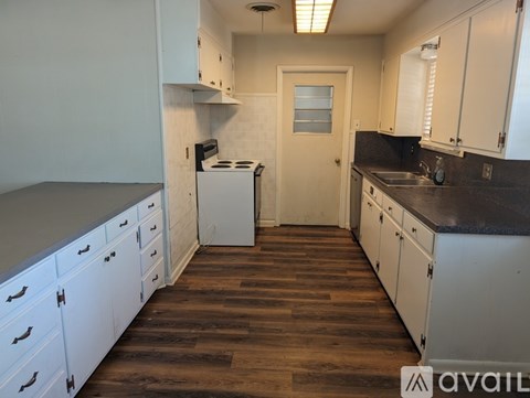 A kitchen with white cabinets and a wooden floor.
