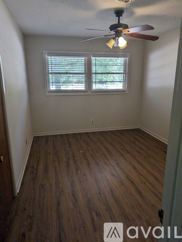 A room with a ceiling fan and wooden flooring.