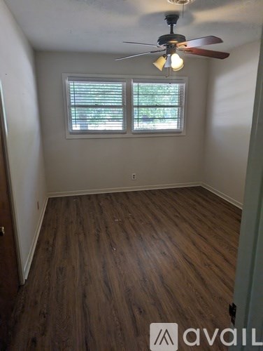 A room with a ceiling fan and wooden flooring.