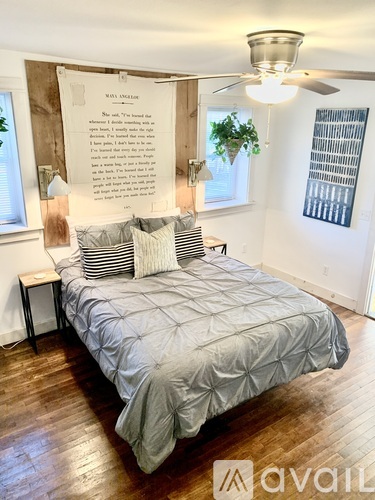 A bedroom with a bed, a ceiling fan, and a wall with a quote on it.