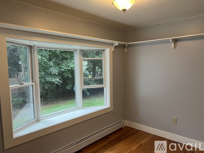 A room with a large window and wooden flooring.