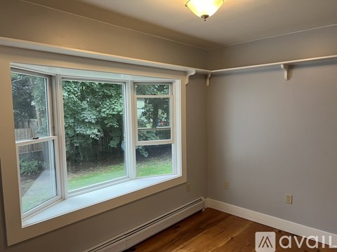 A room with a large window and wooden flooring.
