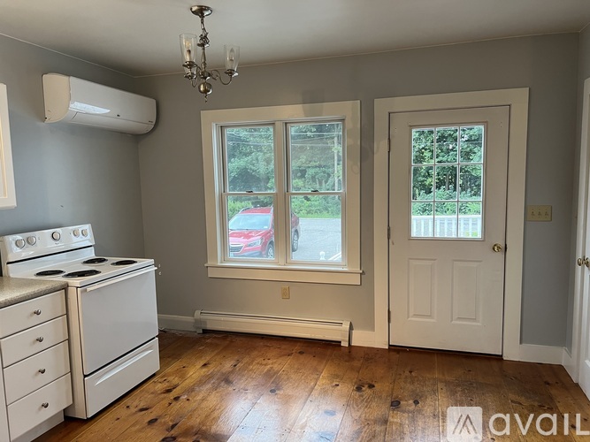 A room with a stove, a chandelier, and a window.