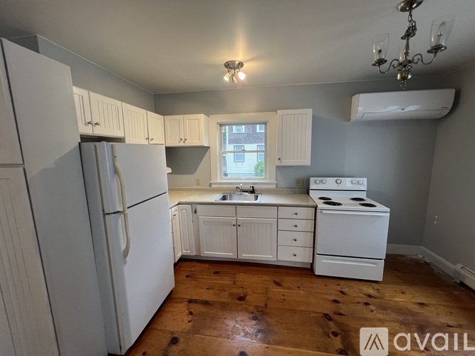 A kitchen with white appliances and wooden floors.