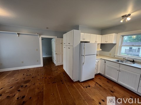 A kitchen with white cabinets and a white refrigerator.