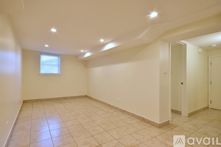 A spacious room with beige tiles and a window.