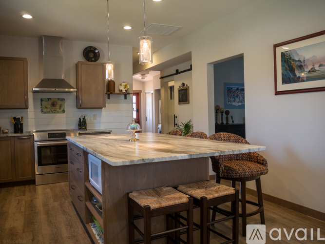 A kitchen with a marble countertop and wooden bar stools.