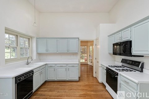 A kitchen with white cabinets and black appliances.
