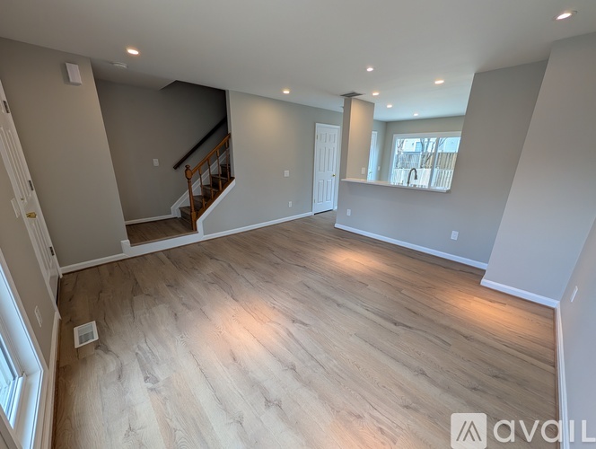 A spacious room with wooden flooring and a staircase leading to another level.