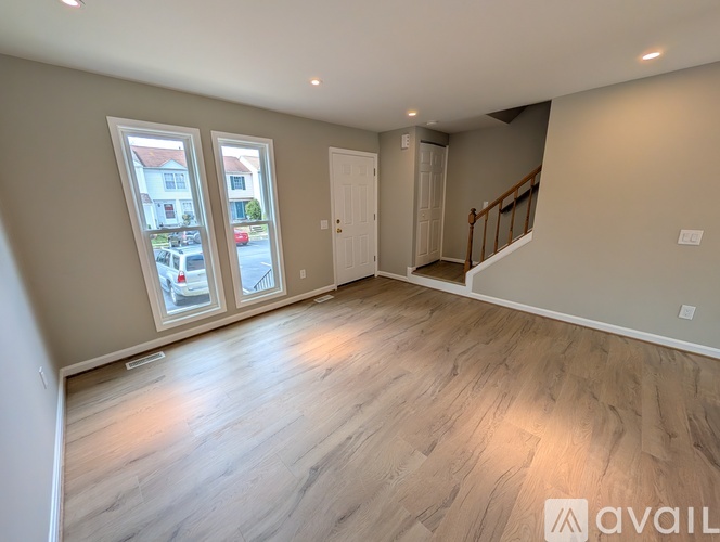 A spacious room with wooden flooring and a staircase.