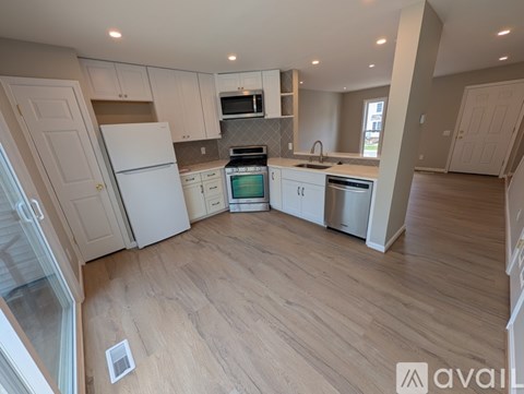 A kitchen with white appliances and wooden floors.
