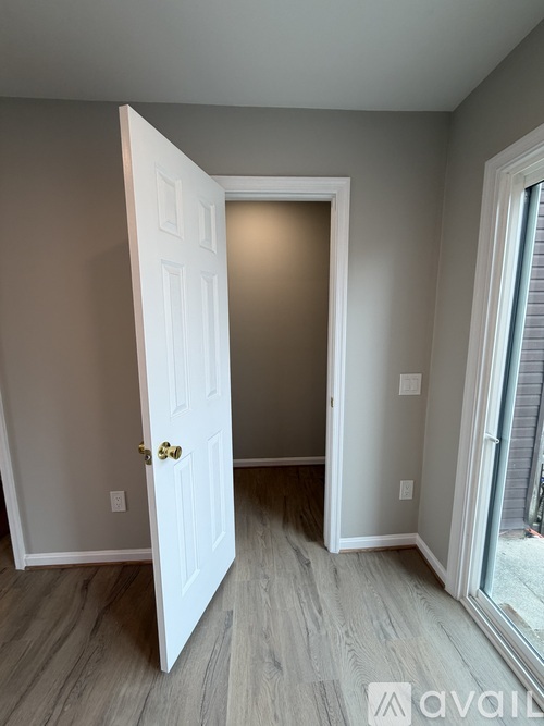 A white door is open to a room with a wooden floor.