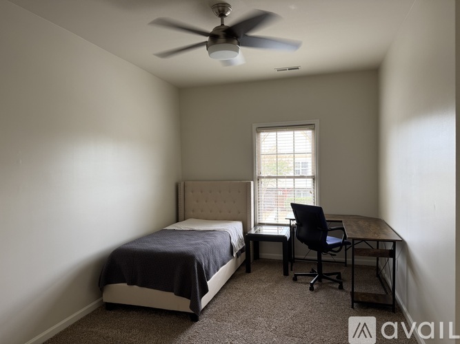 A bedroom with a bed, desk, and chair.