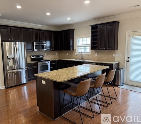 A kitchen with dark brown cabinets and a granite countertop.