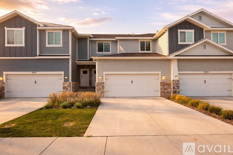 A modern house with a grey and white exterior and a large driveway.