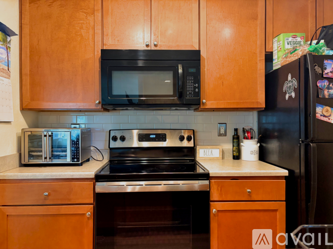 A kitchen with a black microwave above a stove and a black refrigerator.